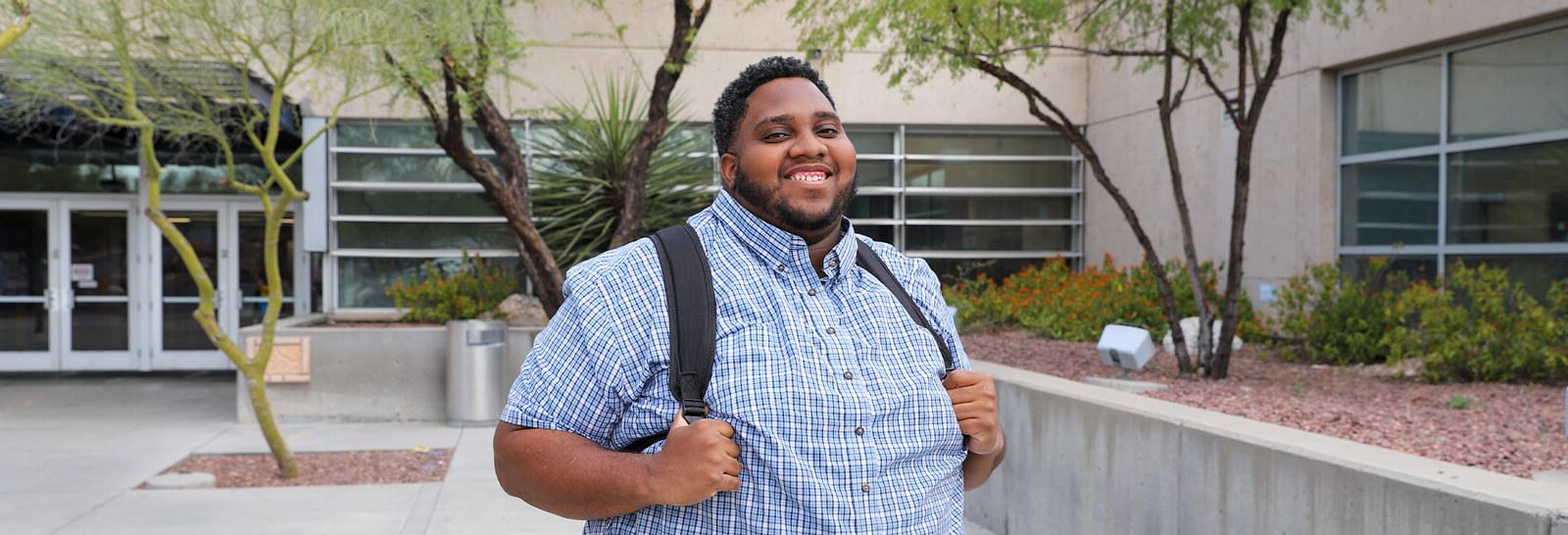 Caleb Bailey stands smiling in front of Pima's West Campus