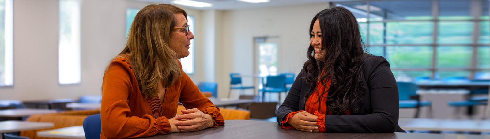 Two students sit smiling in a Pima campus student lounge