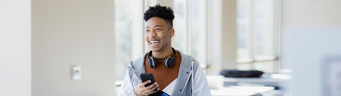 A student smiles while walking through school halls on his phone